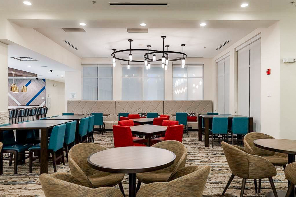 Modern hotel lobby and dining area with red and turquoise chairs