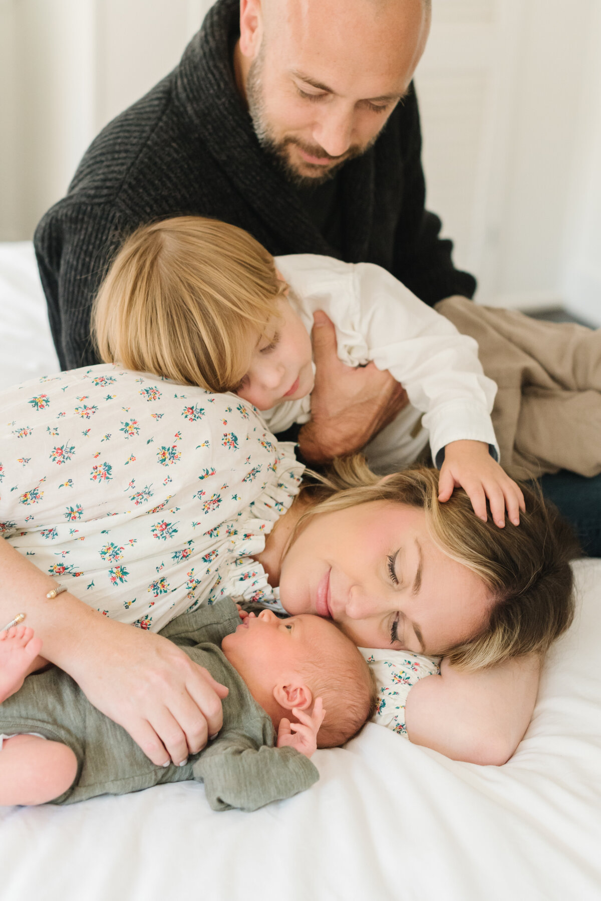 Family cuddling with newborn on bed - Northern Virginia Newborn Photographer