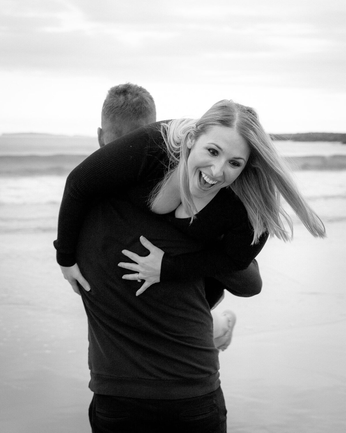 Loving romantic beach shot of a two lovers. The woman is across the mans shoulders.