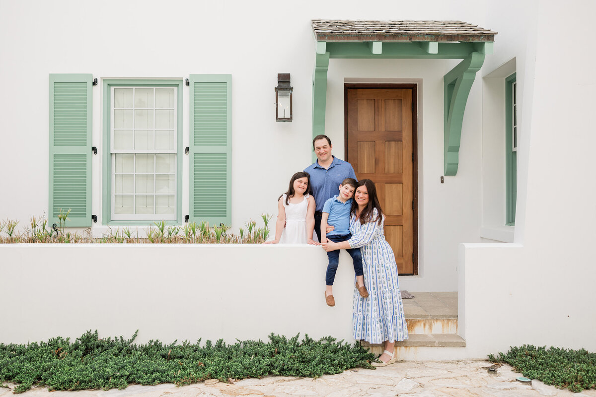 Family of four standing on front porch of home on Seven Wells Court  in Alys Beach.