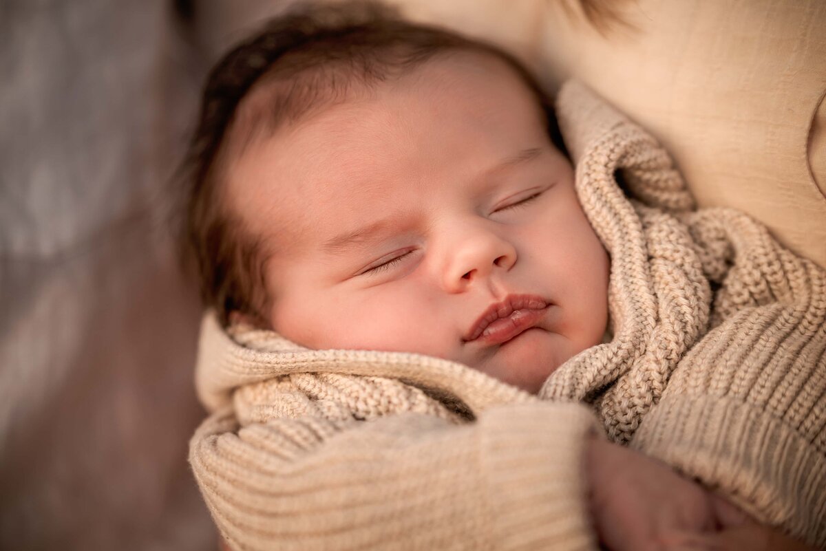 sleeping two week old baby in oatmeal coloured cardigan