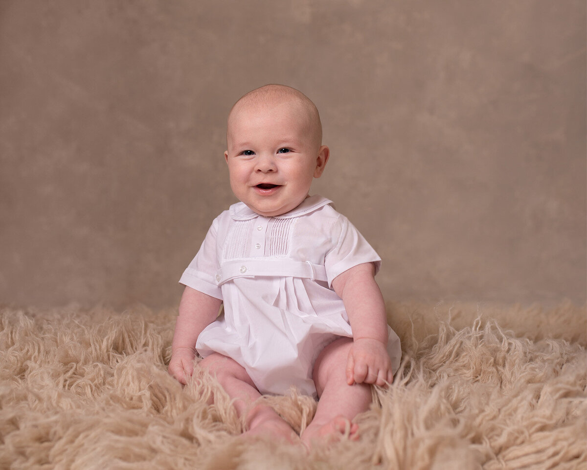 Adorable baby wearing a white outfit from Feltman brothers