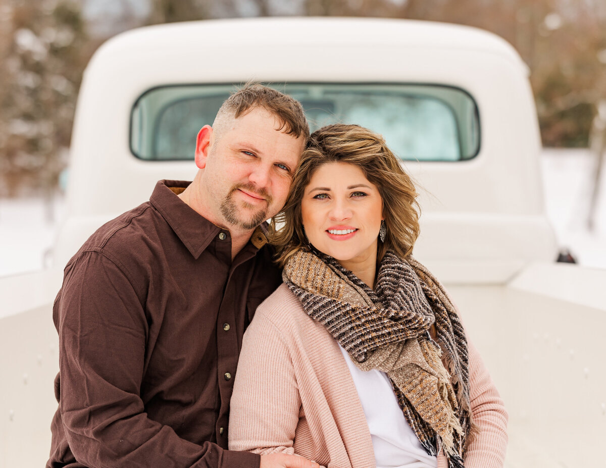 Couple sitting close together in a white vintage truck in the snow outdoors in North East, PA.