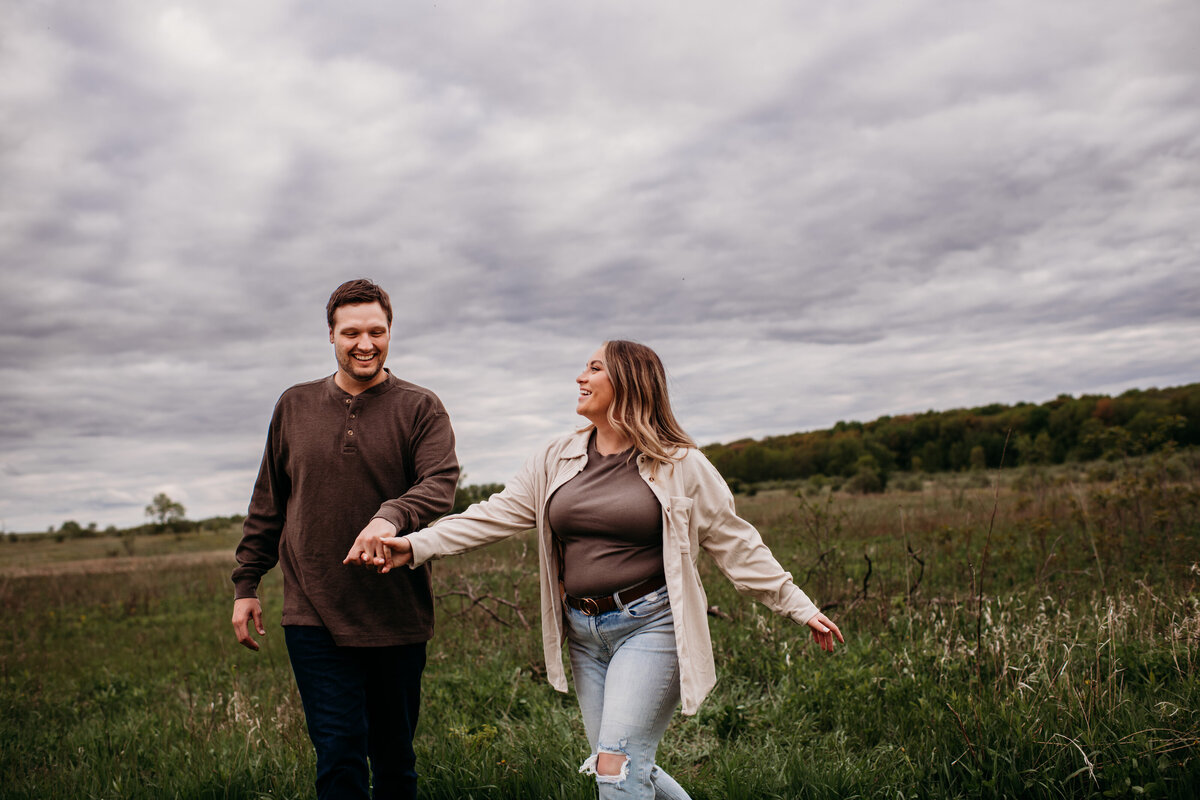 Man and woman holding hands and walking through field