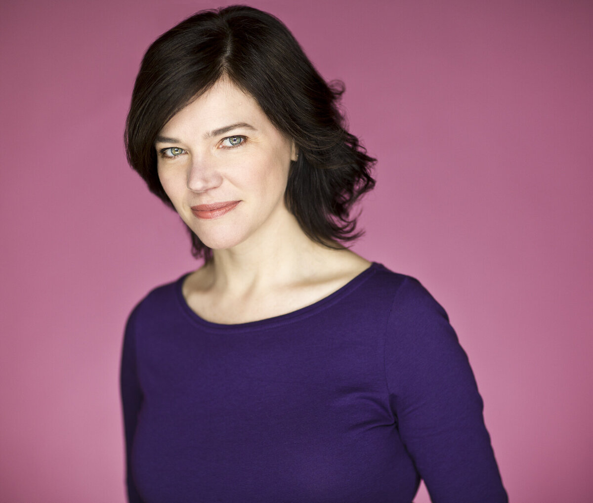 headshot of M.J. Johnson wearing a purple shirt in front of a pink background.