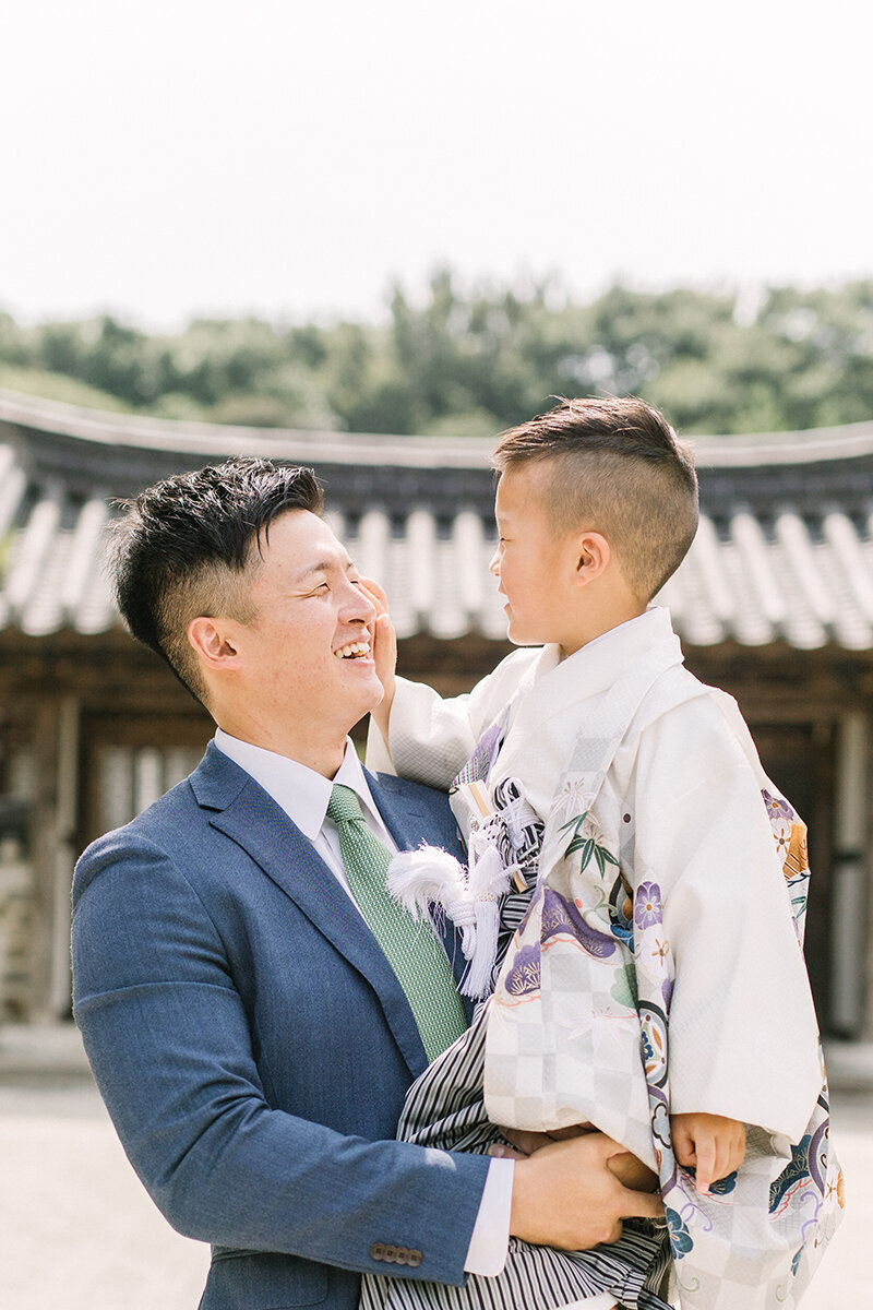 パパが袴姿の七五三の男の子を抱っこして満面の笑みで笑っている素敵な七五三家族写真。