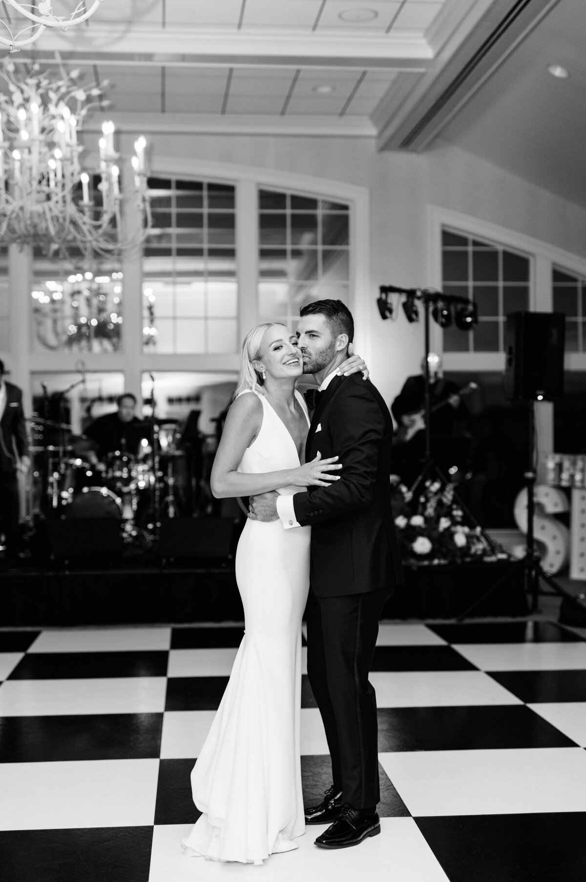 Bride and groom first dance on checkered dance floor with live band