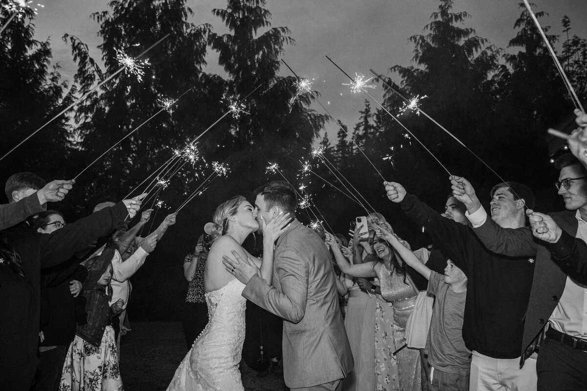 Bride and groom kissing in front of people holding sparklers