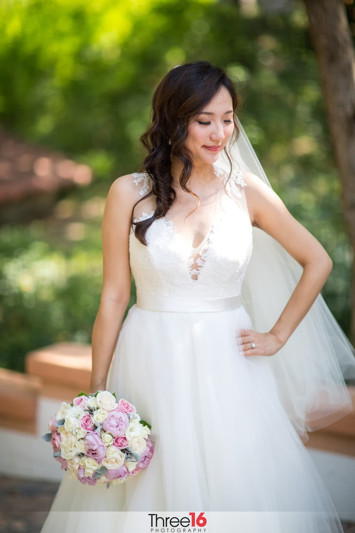 Bride poses looking down with hand on hip during photo session