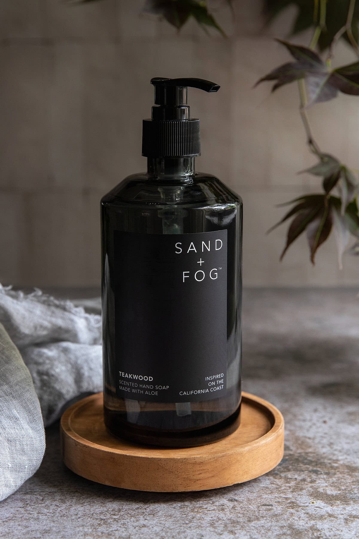 Moody bath and body product photography of Sand + Fog hand soap styled on stone and wood, shot for wellness brands in Richmond Virginia.