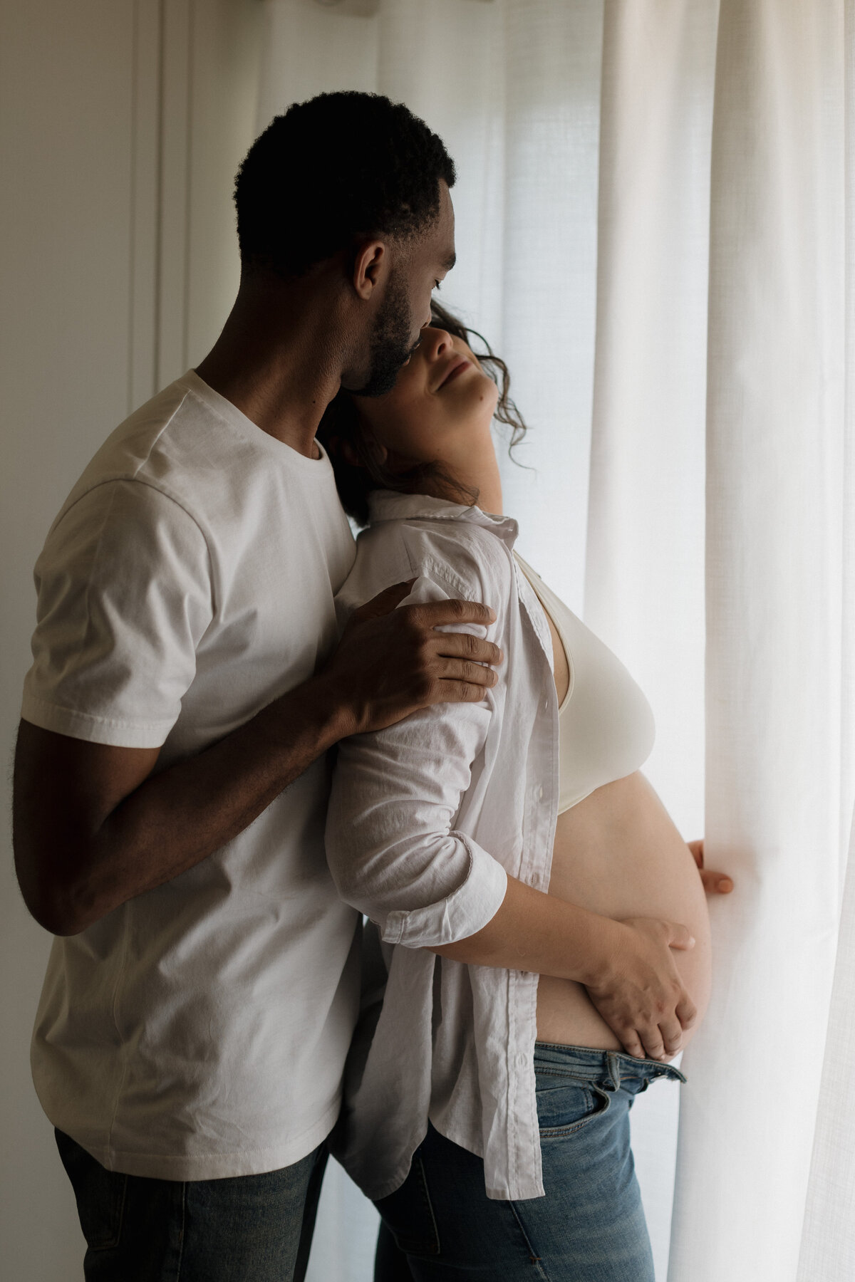 Expectant couple sharing a tender moment, echoing the intimate style of wedding and lifestyle photography focused on genuine connection.