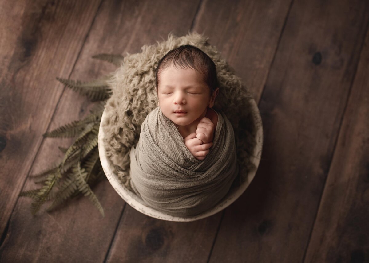 Aerial image. Baby sleeping in basket with natural, olive hues.