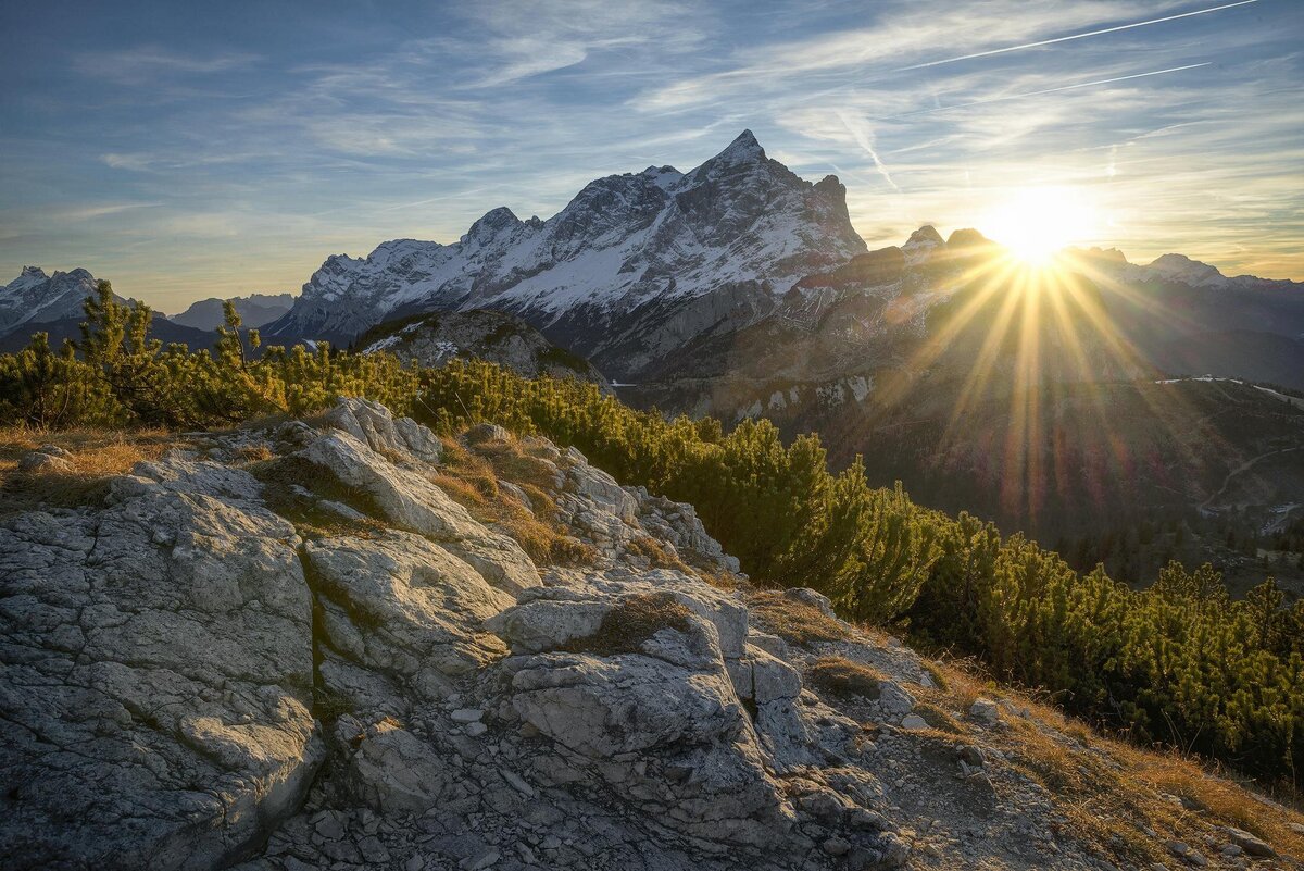 Peak of a mountain with sun shining behind it