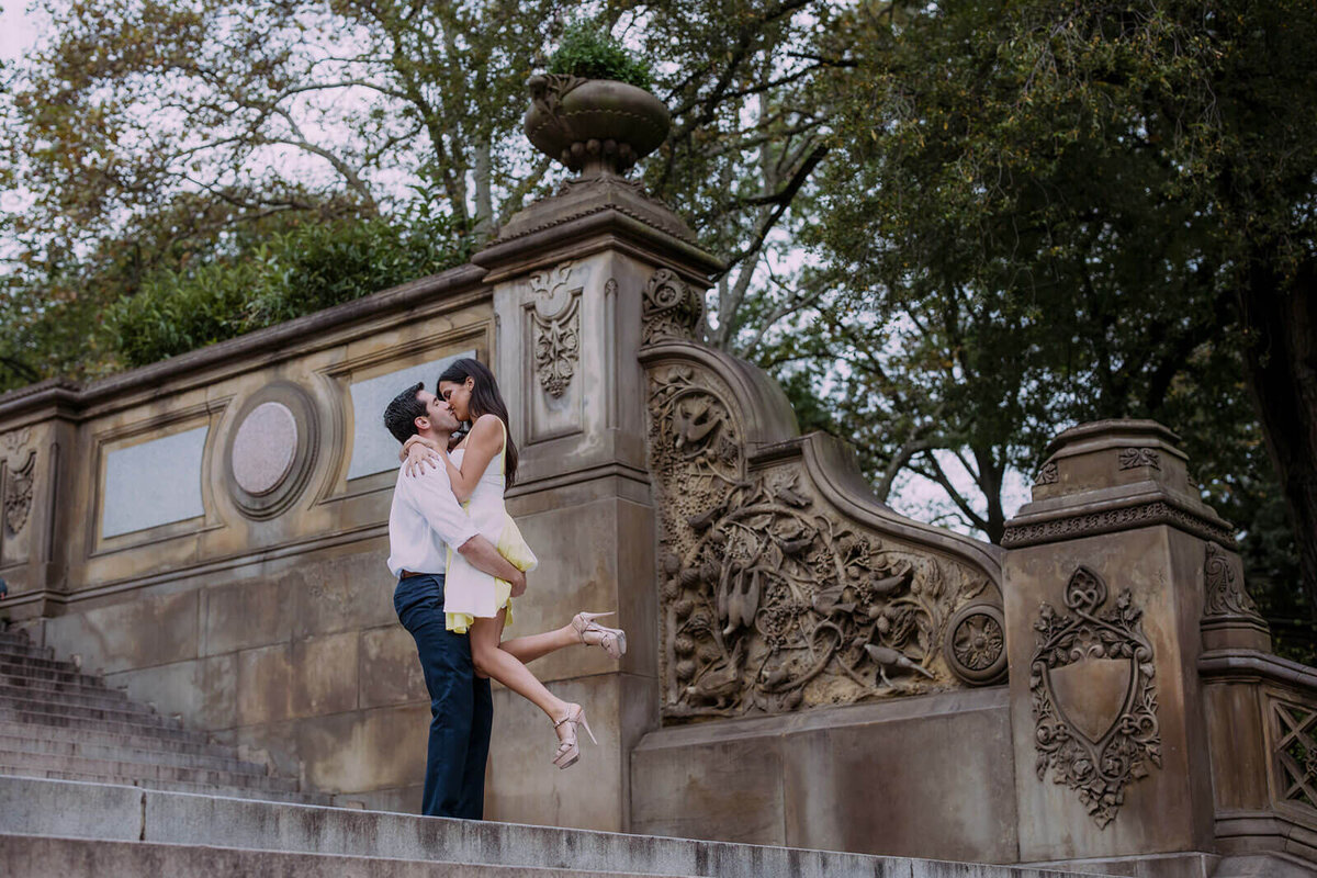 The man is carrying his fiancée on a staircase in Central Park. Image by Jenny Fu Studio