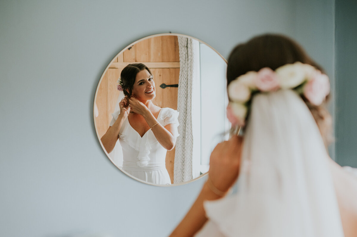 Bride putting on earrings in mirror