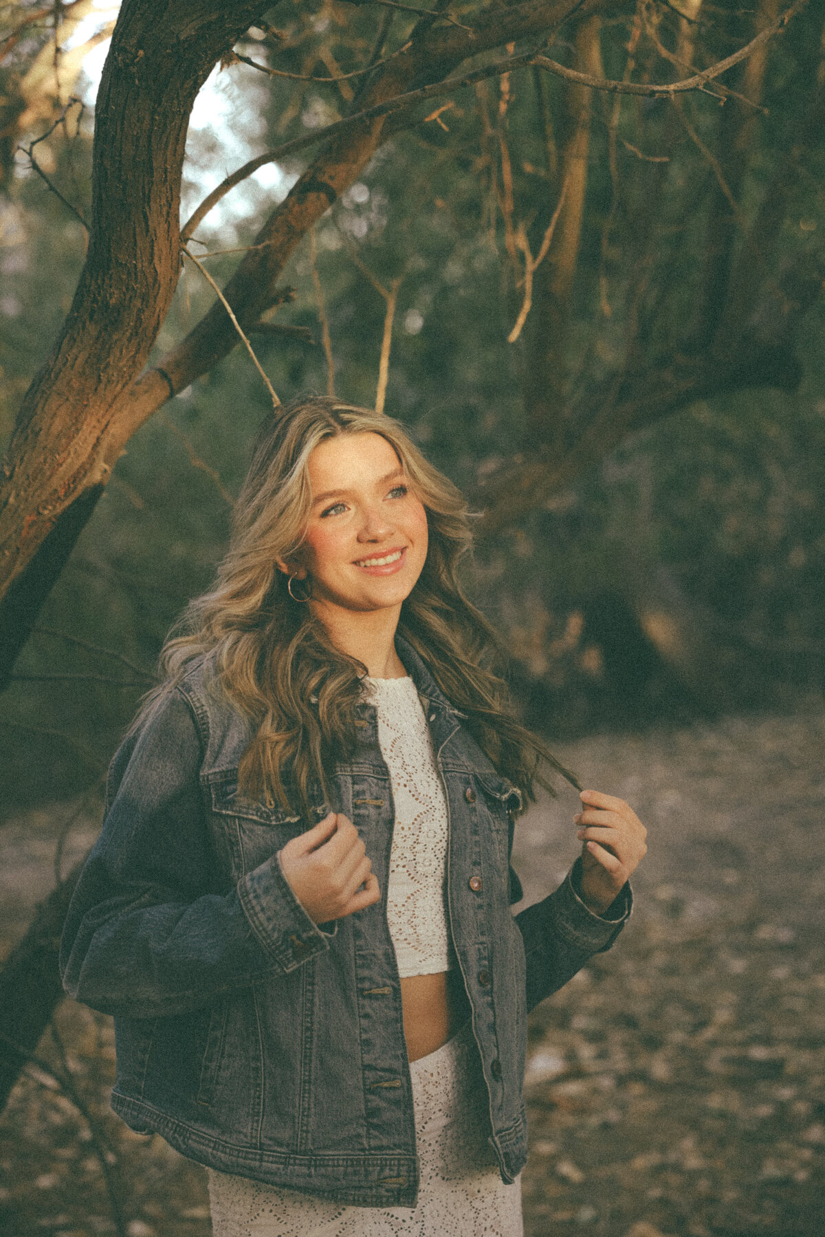 Black and White Artistic Senior Portrait of Girl Walking Down Forest Road Surrounded by Tall Pines