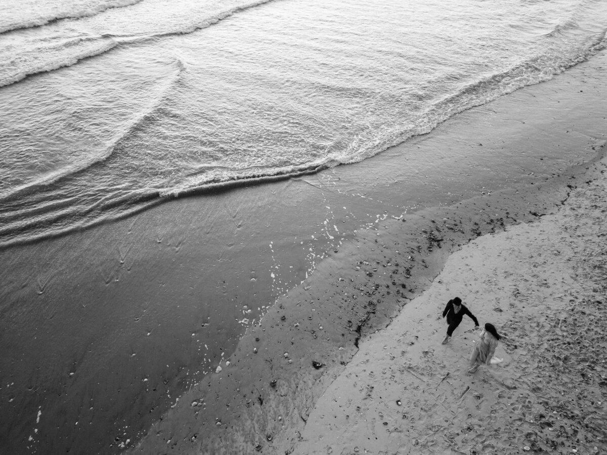 drone photo of a couple walking on the beach