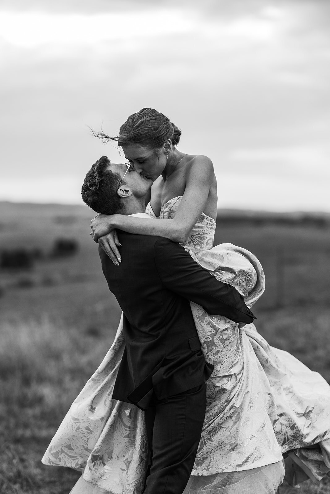 Black and white image of bride and groom kissing during their wedding day sunset photos at Petrichor Farm