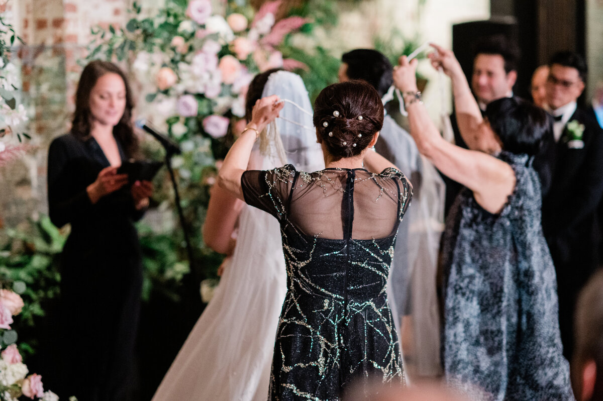 Mother of the bride positions the bride's veil at the altar