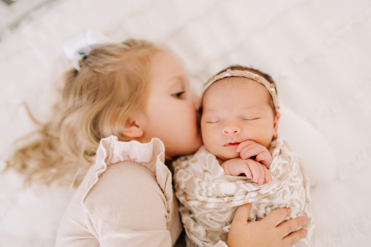 Branson Missouri newborn photogrpahy of mom and newobrn sister laying on bed cuddling