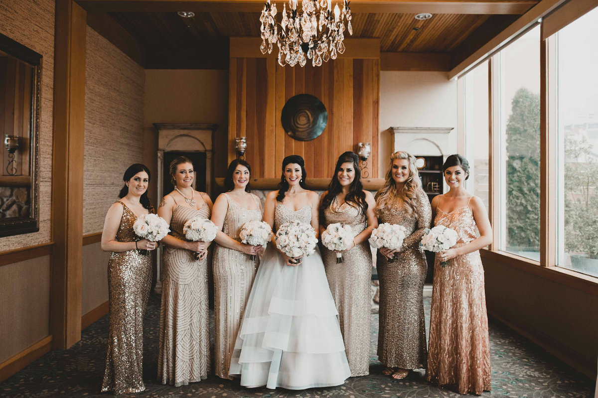 Beautiful bridal party wearing long sparkly dresses at the Edgewater Hotel in Seattle