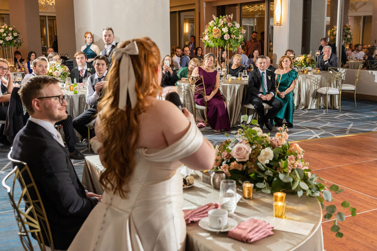 A woman in a wedding dress is speaking into a microphone