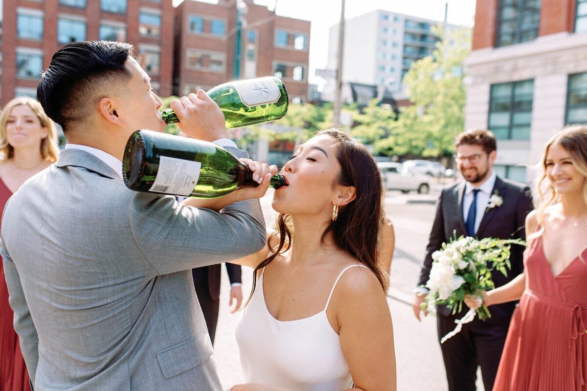 Bride Groom and wedding party celebrate with champagne spray in the downtown Toronto streets happy joyful playful fun spontaneous jacqueline james photography