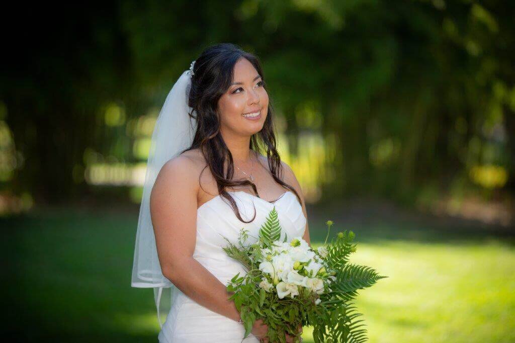 Bride smiles and looks off to the side at captiol park in sacramento, in a photo by philippe studio pro.