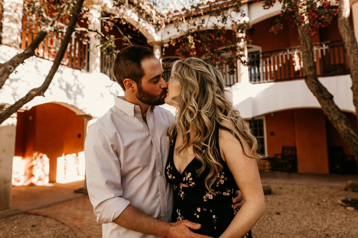 engaged couple kissing in the middle of a courtyard