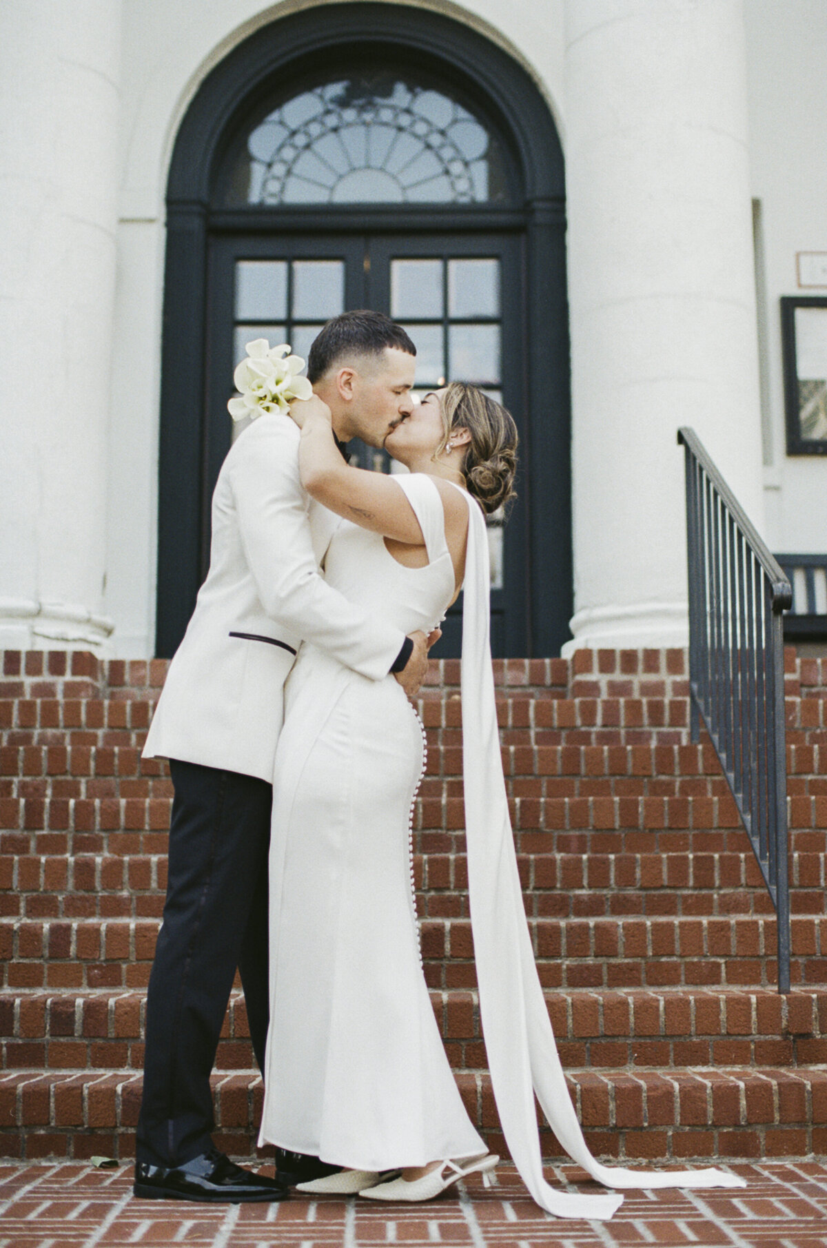 Couple kissing on the steps of Tarrytown House Estate on their wedding day, shot on 35mm film