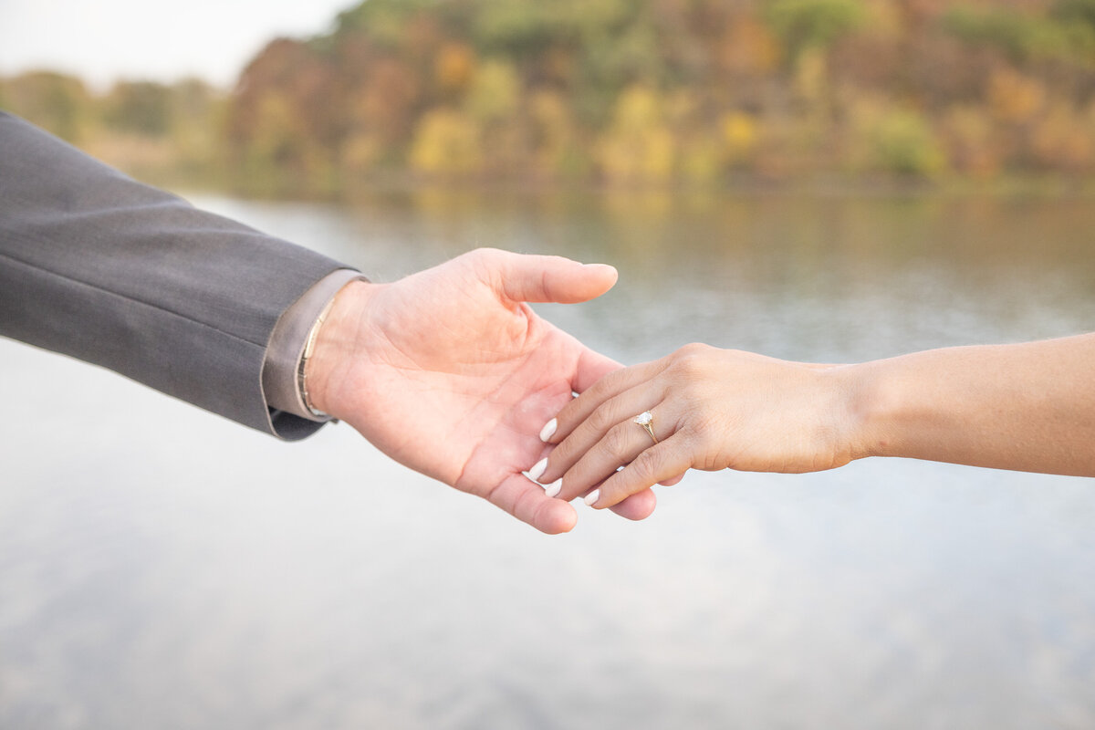 Engagement ring with lake in background during the fall
