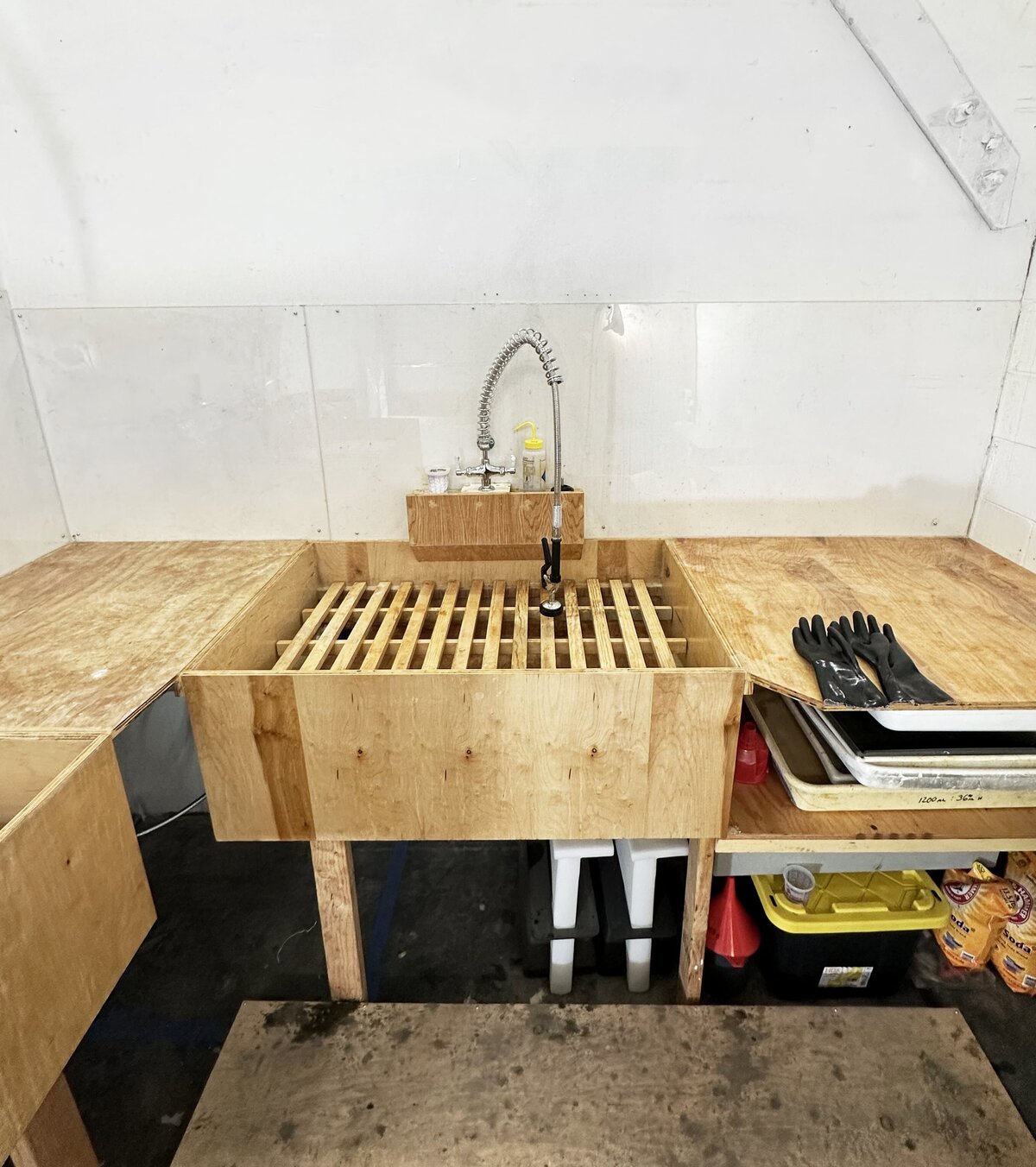 A well-ventilated acid etching area with a sink, protective gloves, and safety equipment, essential for the etching process in printmaking.