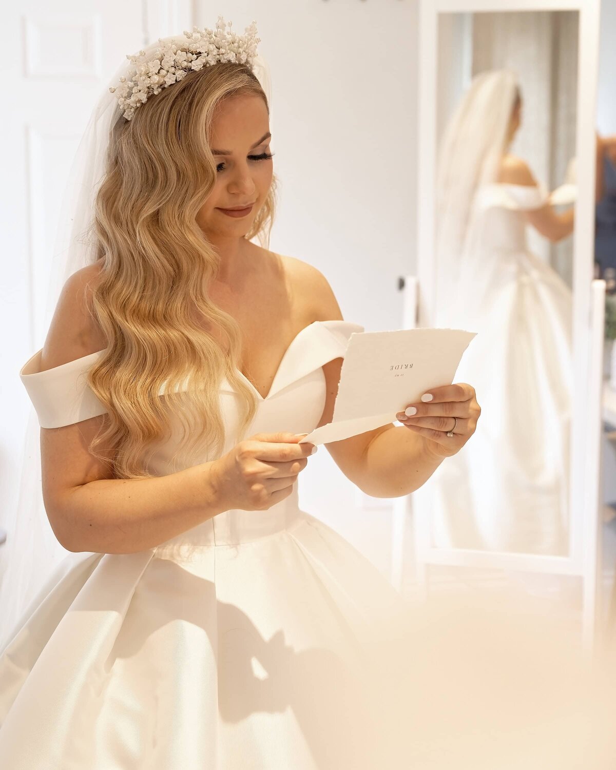 Bride in her wedding dress reading a letter from her groom on the morning of her wedding.