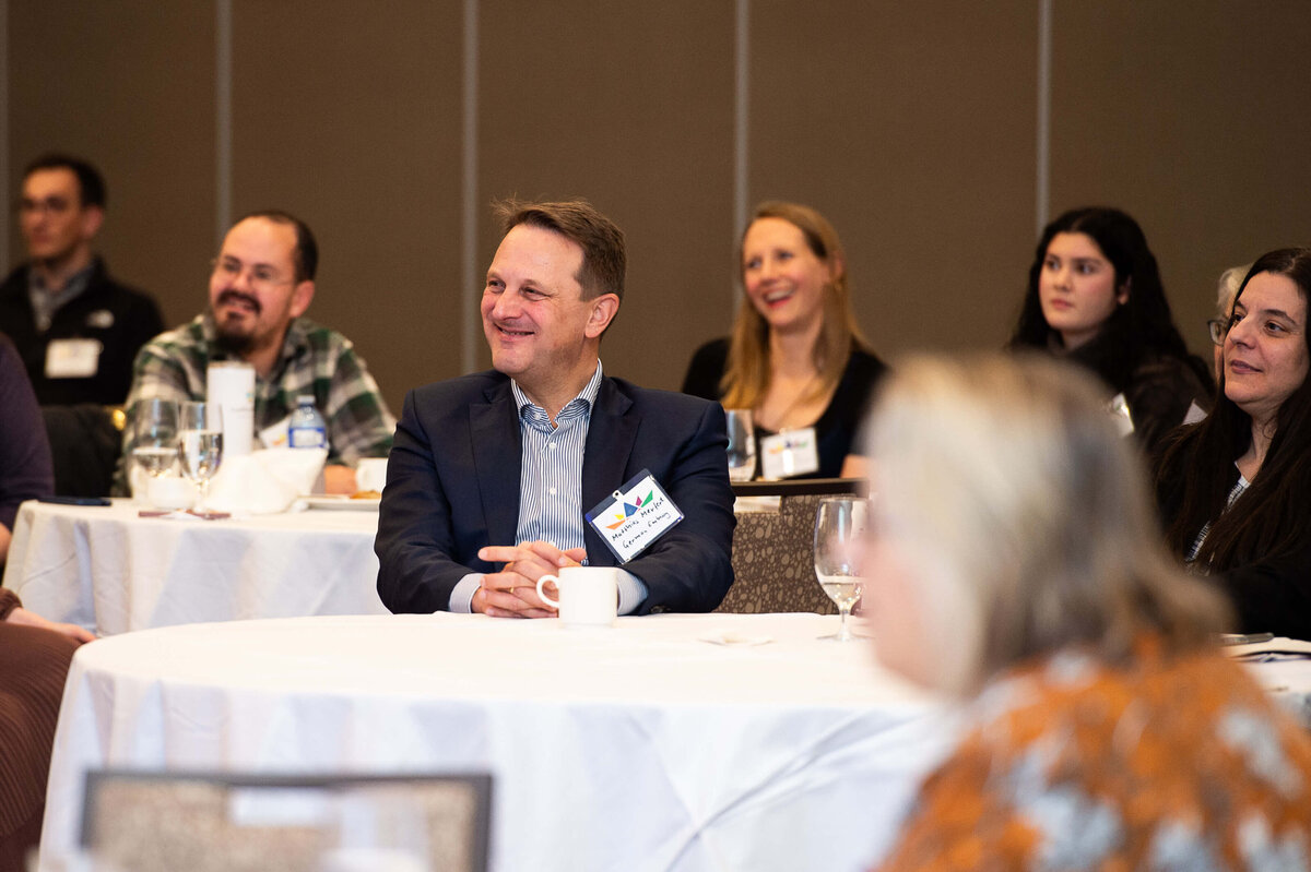 Ottawa event photos of attendees smiling at their tables duing a corporate conference.  Captured by JEMMAN Photography COMMERCIAL