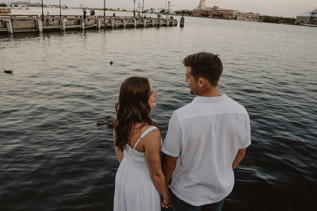 A couple holding hands and standing on the edge of the water 