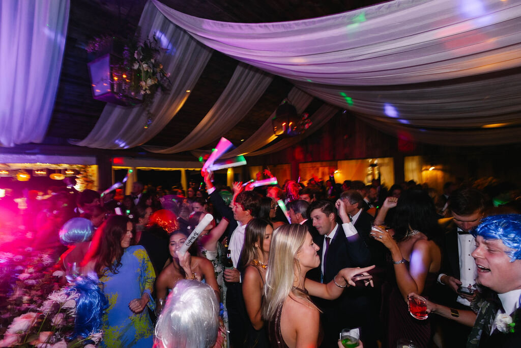 Guests dancing under draped fabric ceilings with glow sticks during a lively wedding reception at The Bascom in Highlands, North Carolina.