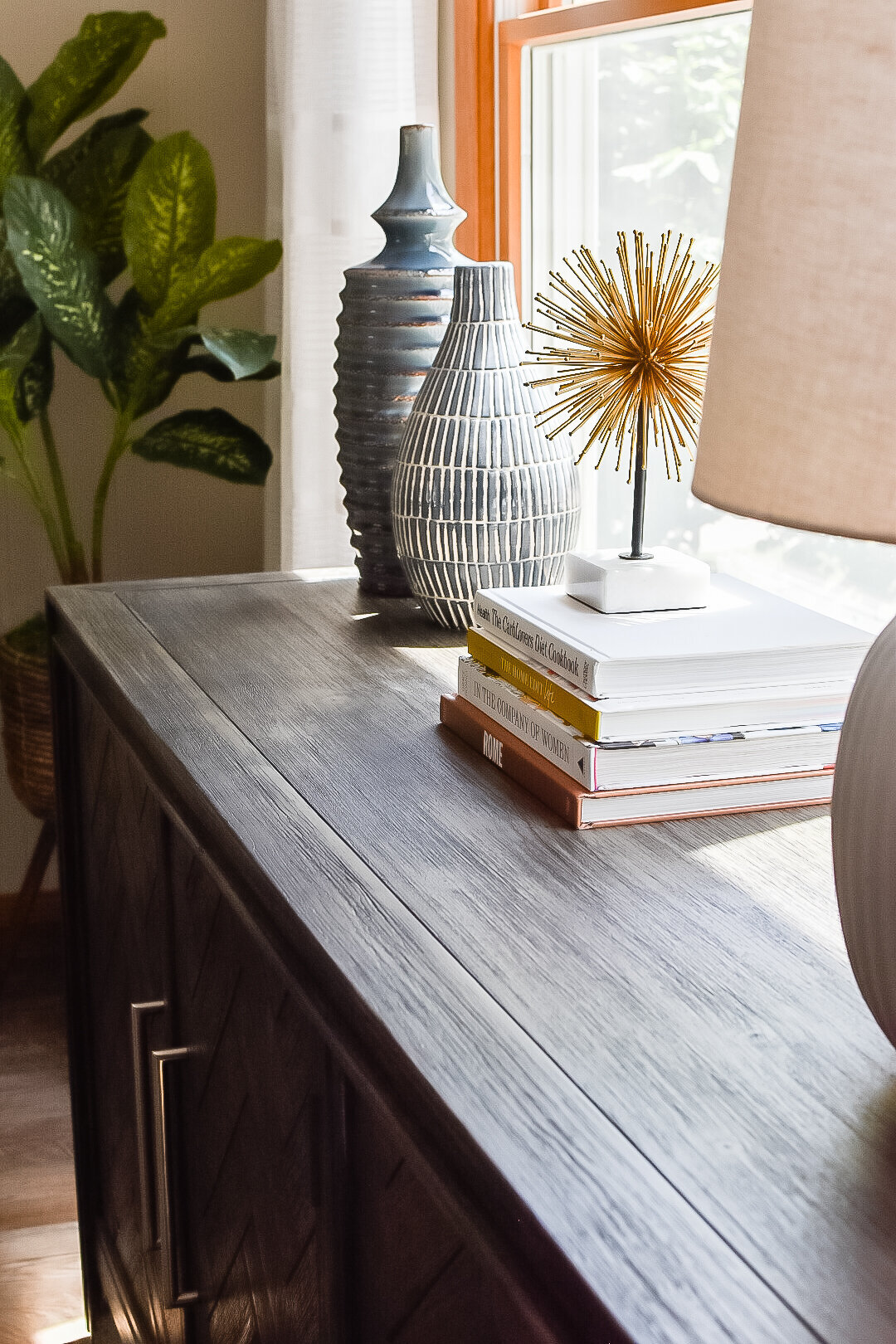 Stacked coffee table books sit on a living room console