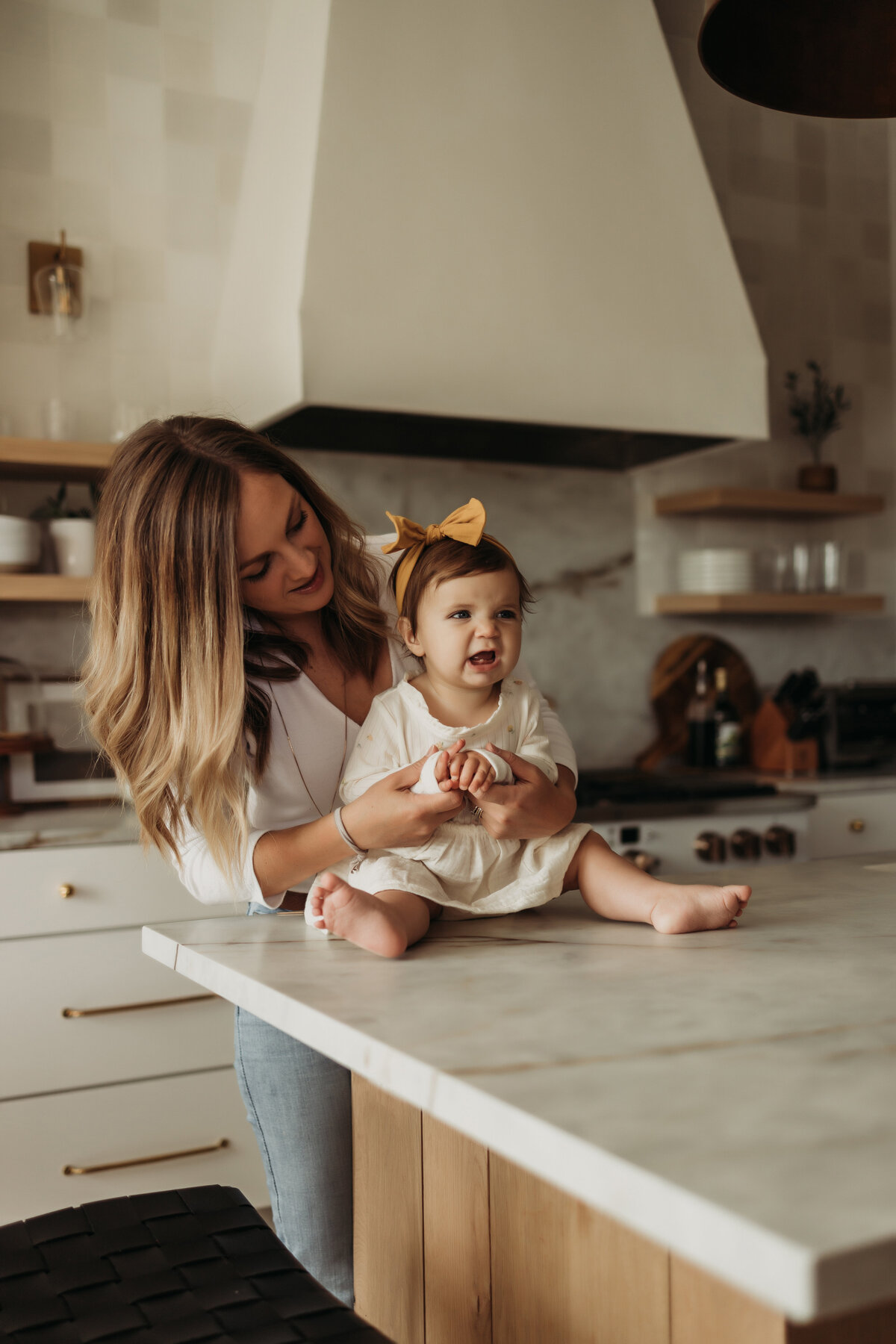 Mom plays with toddler girl while sitting on updated kitchen island