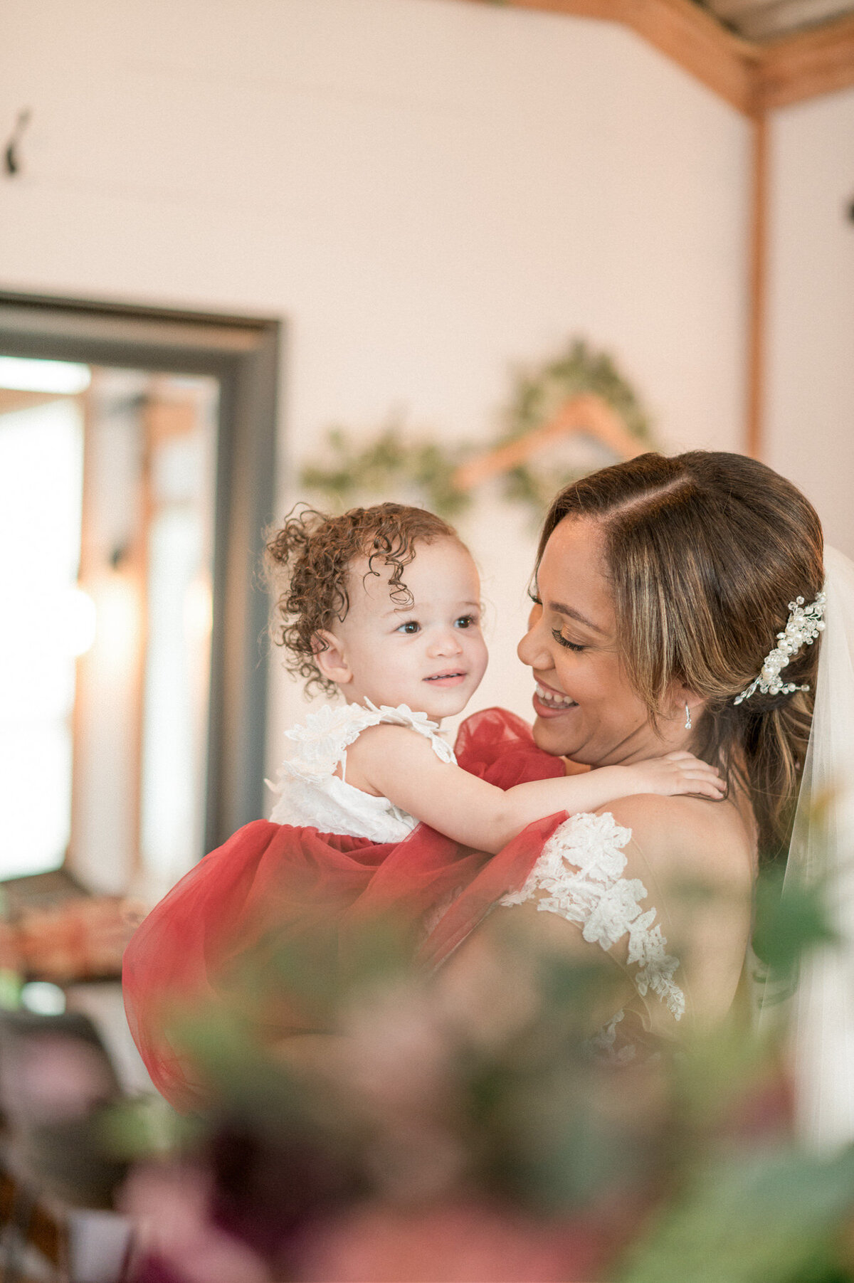The bride, after getting ready for her wedding, holds her flower girl niece and gives her a hug