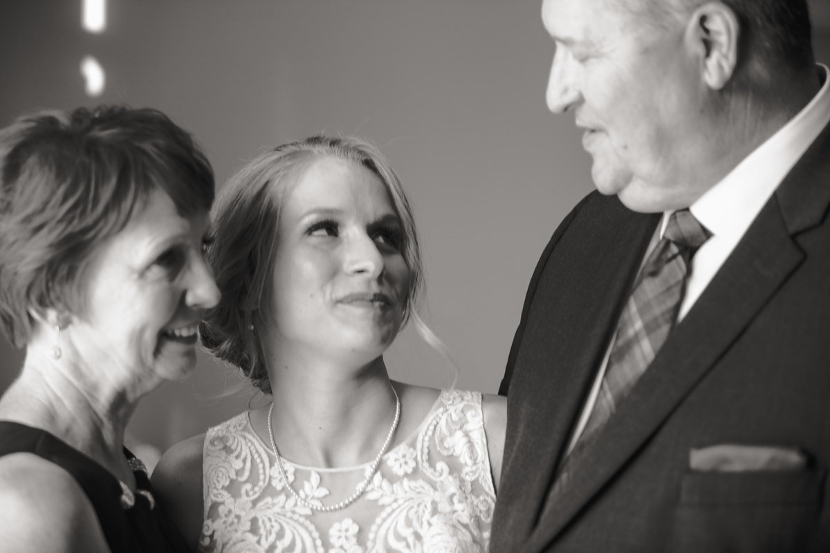 Bride and her parents share a moment before the wedding ceremony.
