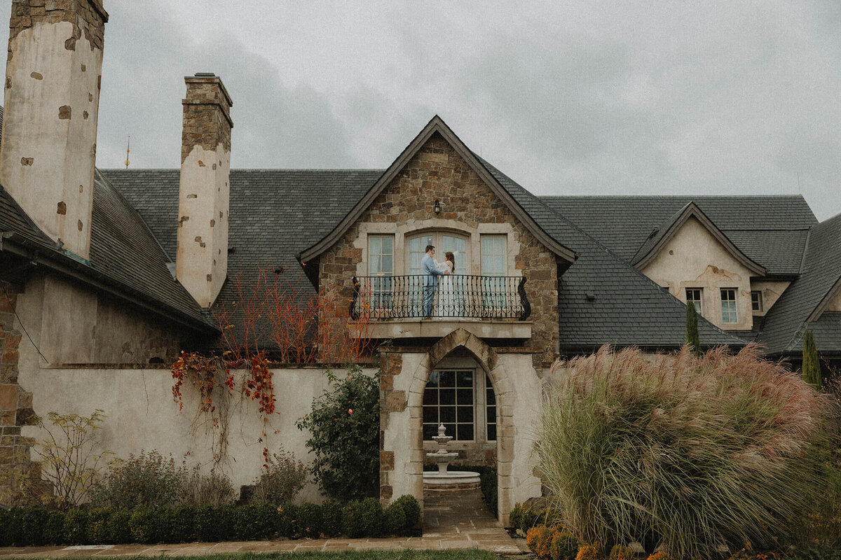 A bride and groom embrace standing on the balcony of the Chateau wedding venue in Oregon.