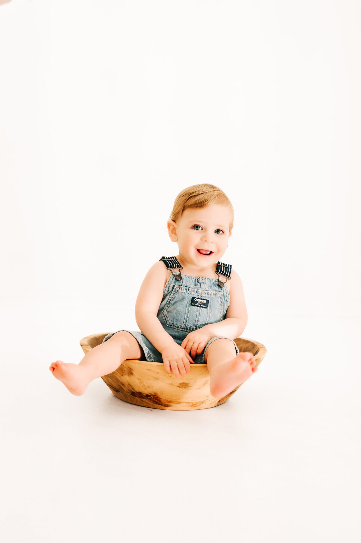 1st birthday photography session of toddler boy sitting in bowl laughing captured by Springfield MO kids photographer