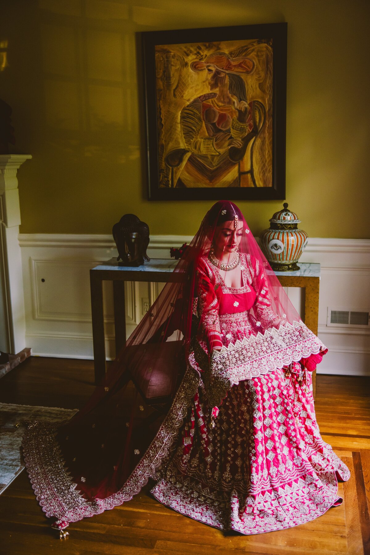 A sikh bride during her bridal prep getting ready and sitting with the dupatta veil over her head