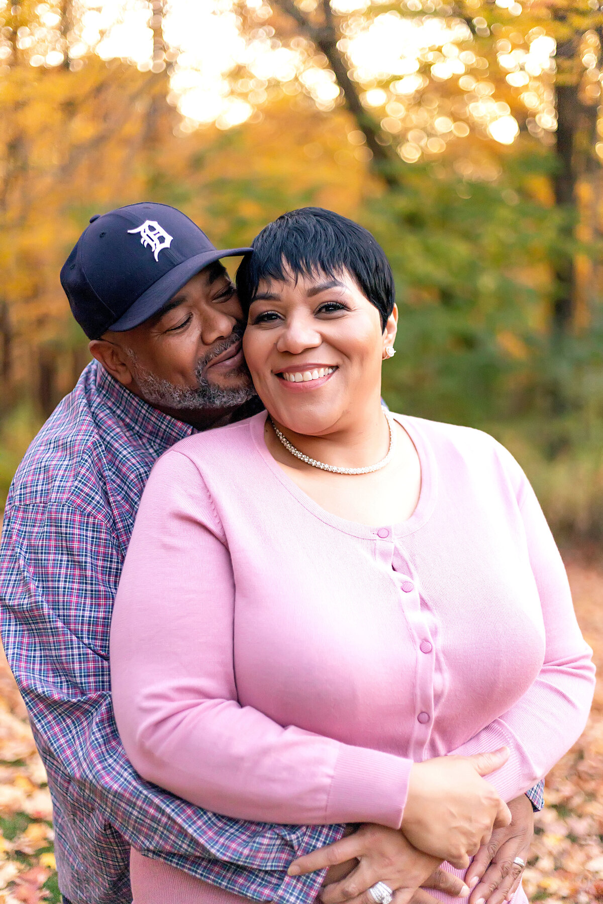 Husband standing behind wife with arms wrapped around her waist outside