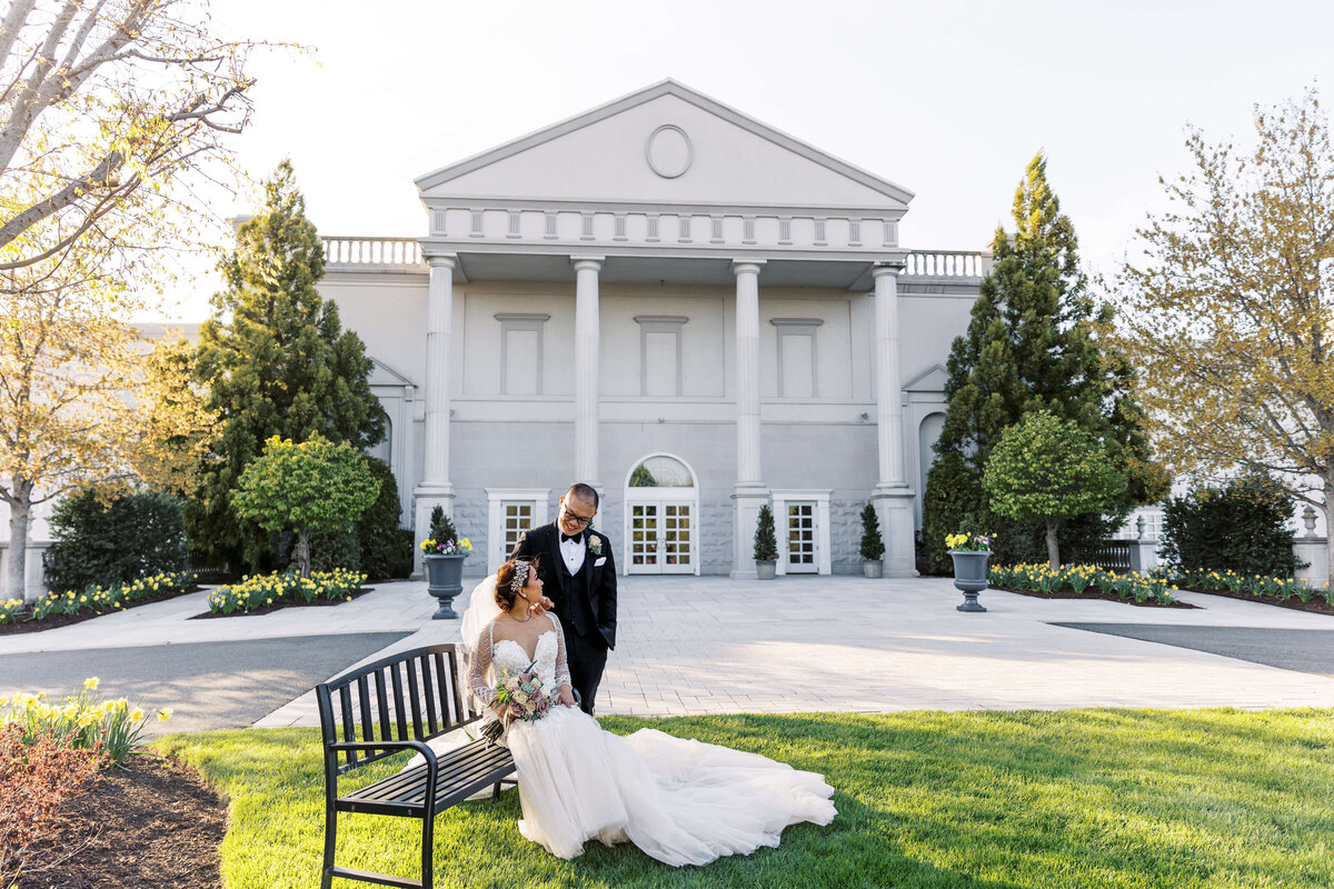 Bride and groom sit in front of their wedding venue, Palace at Somerset Park during sunset.