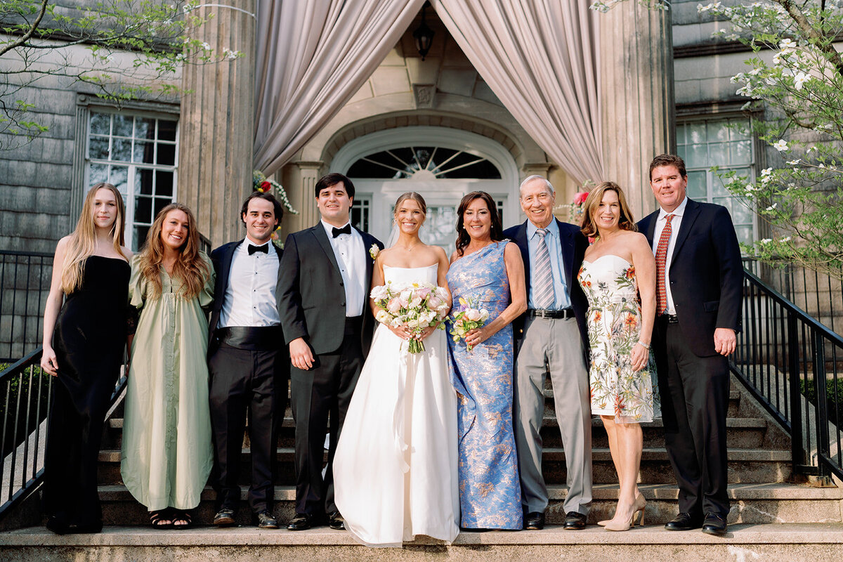 Bride and groom standing with their family on the stone steps of Burritt on the Mountain, smiling in front of the draped ceremony entrance.
