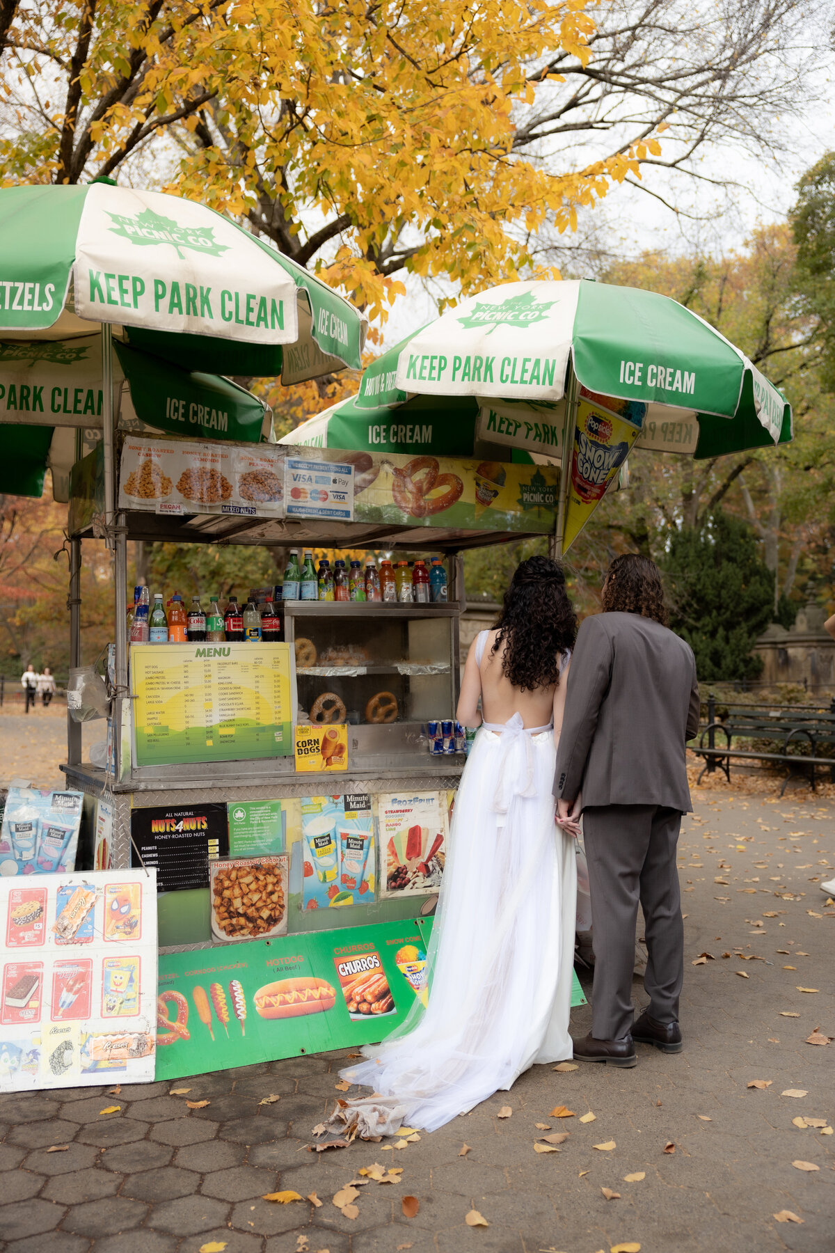 The bride laughing joyfully while holding her bouquet among autumn leaves in Central Park.