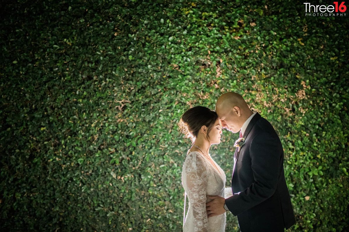 Sweet Bride and Groom moment at night in front of an ivy covered wall