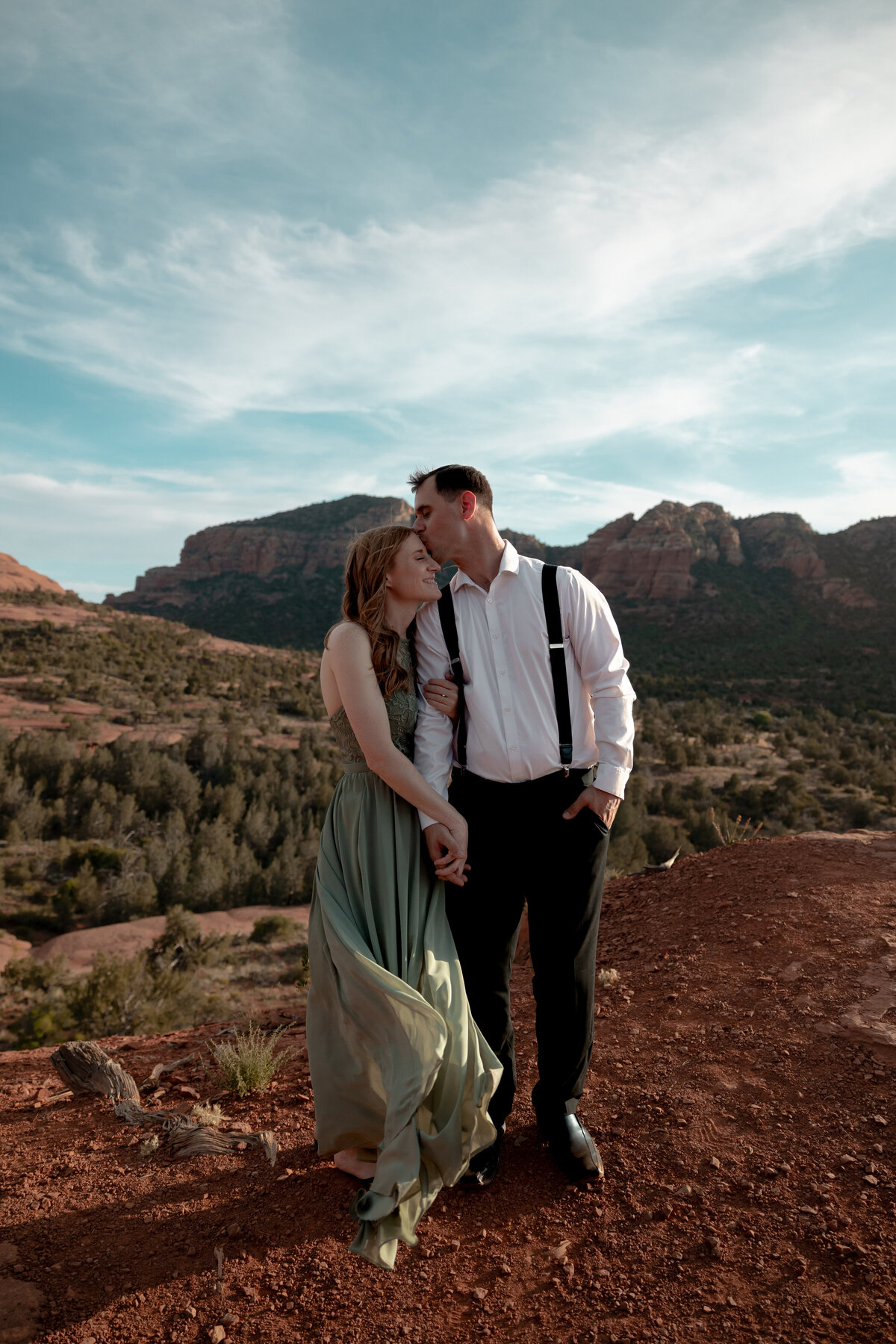 Couple standing against red rock backdrop during Sedona engagement session
