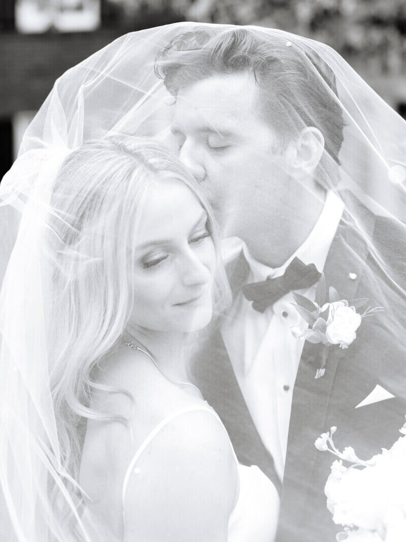 Groom kissing bride under veil planned by wedding planners chicago il